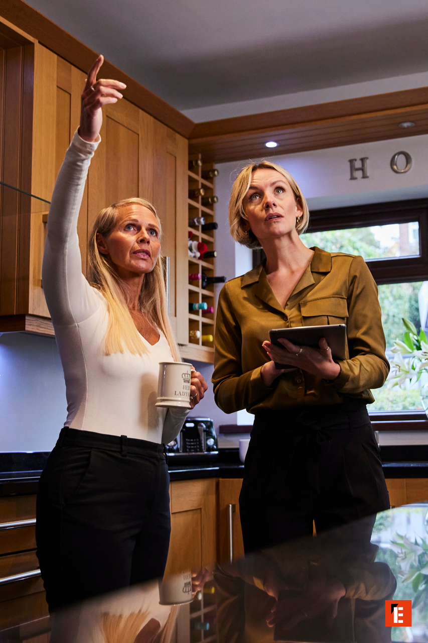 two women inspecting modern kitchen with tablet