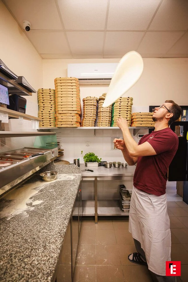 sztuka podrzucania ciasta do pizzy w profesjonalnej kuchni