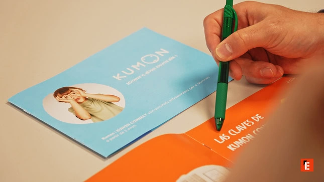 hand pointing at kumon brochures with pen
