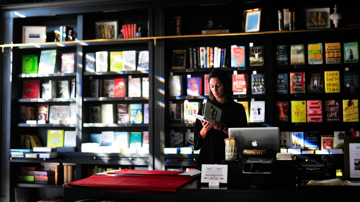 lettore al banco della libreria illuminato dal sole