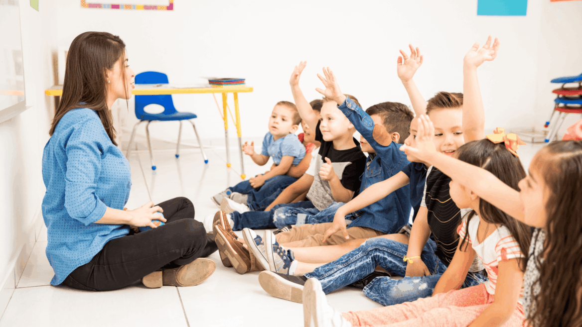 maestra y niños preescolares con manos levantadas