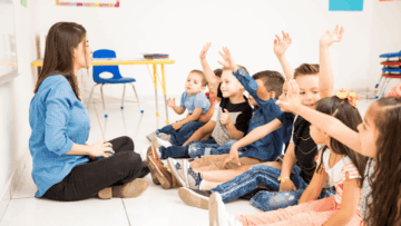 maestra y niños preescolares con manos levantadas