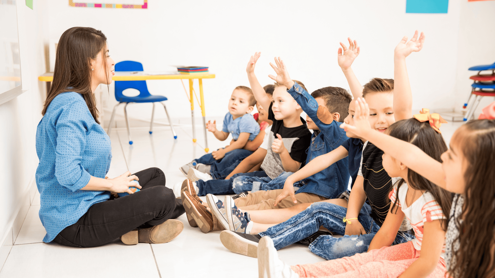 maestra y niños preescolares con manos levantadas