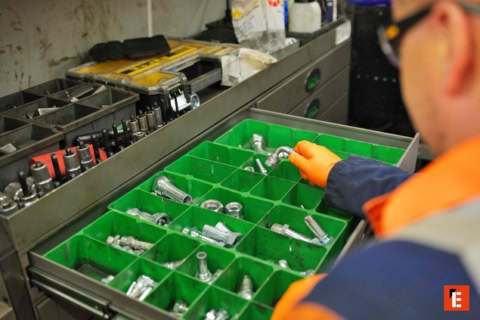 workshop technician selecting metal fittings from drawer
