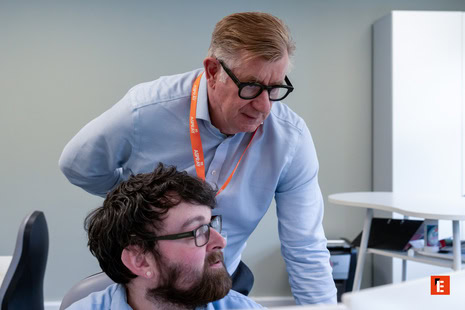 senior mentor guiding junior colleague at computer