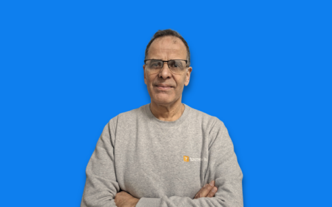 portrait dhomme souriant en sweat gris, fond bleu