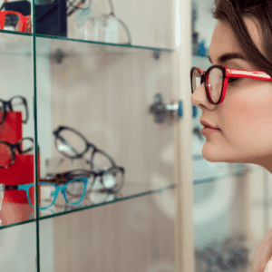 mujer probándose gafas rojas en Óptica moderna