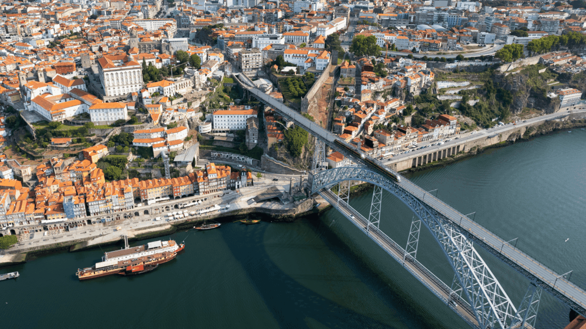 puente de arco sobre río y ciudad de tejados rojos