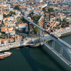 puente de arco sobre río y ciudad de tejados rojos