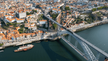puente de arco sobre río y ciudad de tejados rojos