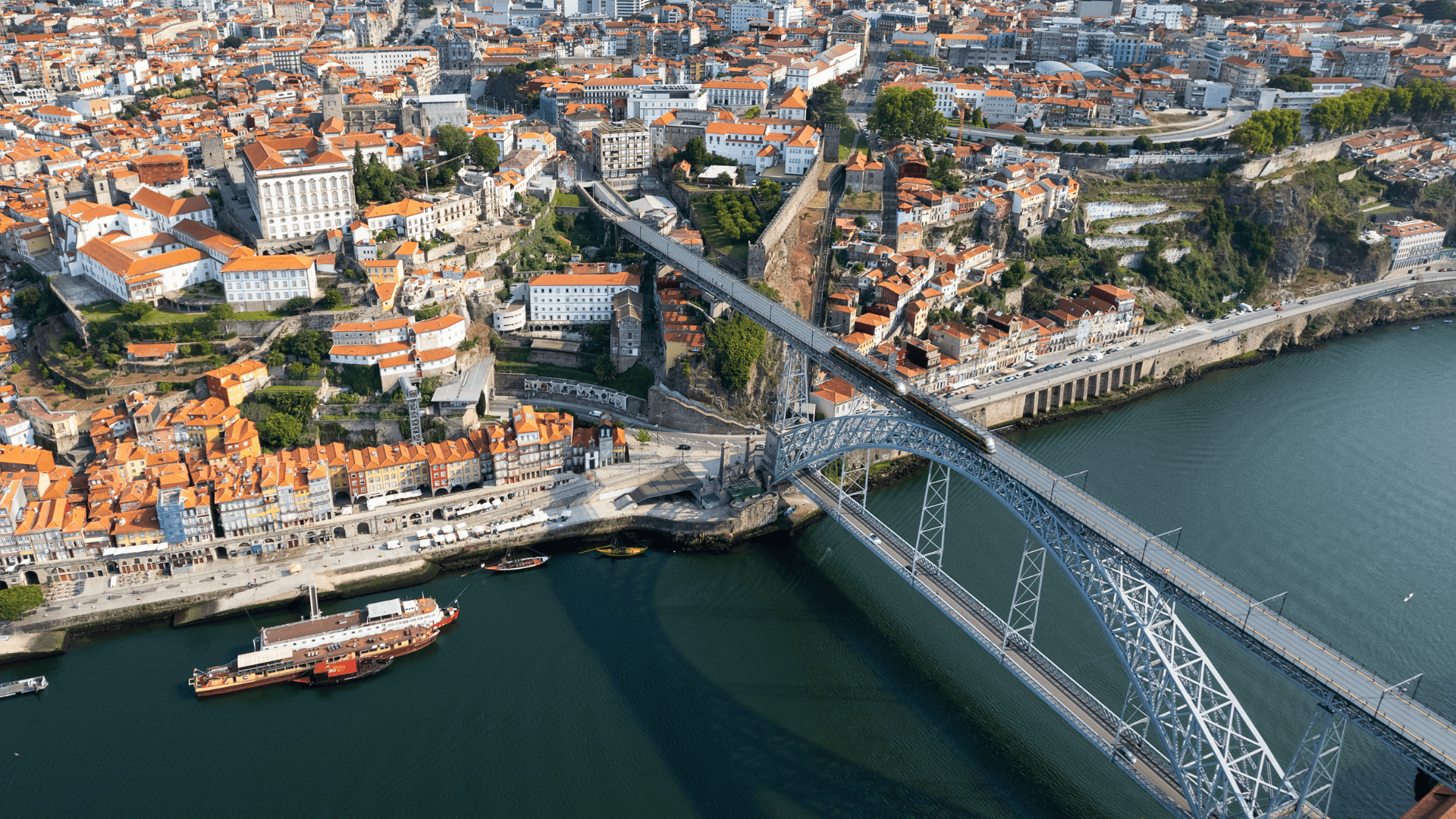 puente de arco sobre río y ciudad de tejados rojos