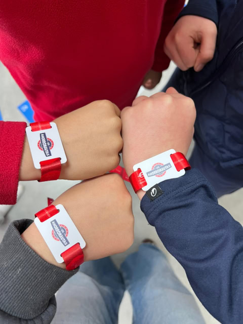 manos unidas con pulseras rojas de los ahorronautas