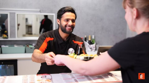 camarero sonriente entrega sushi para llevar