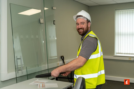 smiling construction worker in hard hat at site meeting