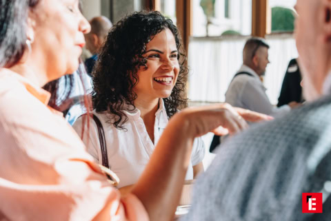 mujer sonriente en café lleno de conversación