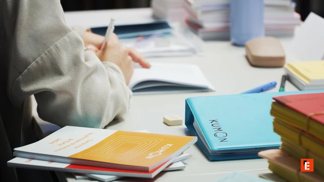 student writing in kumon workbook at desk