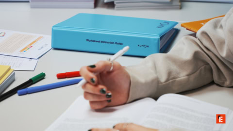 hand writing at study desk with kumon binder
