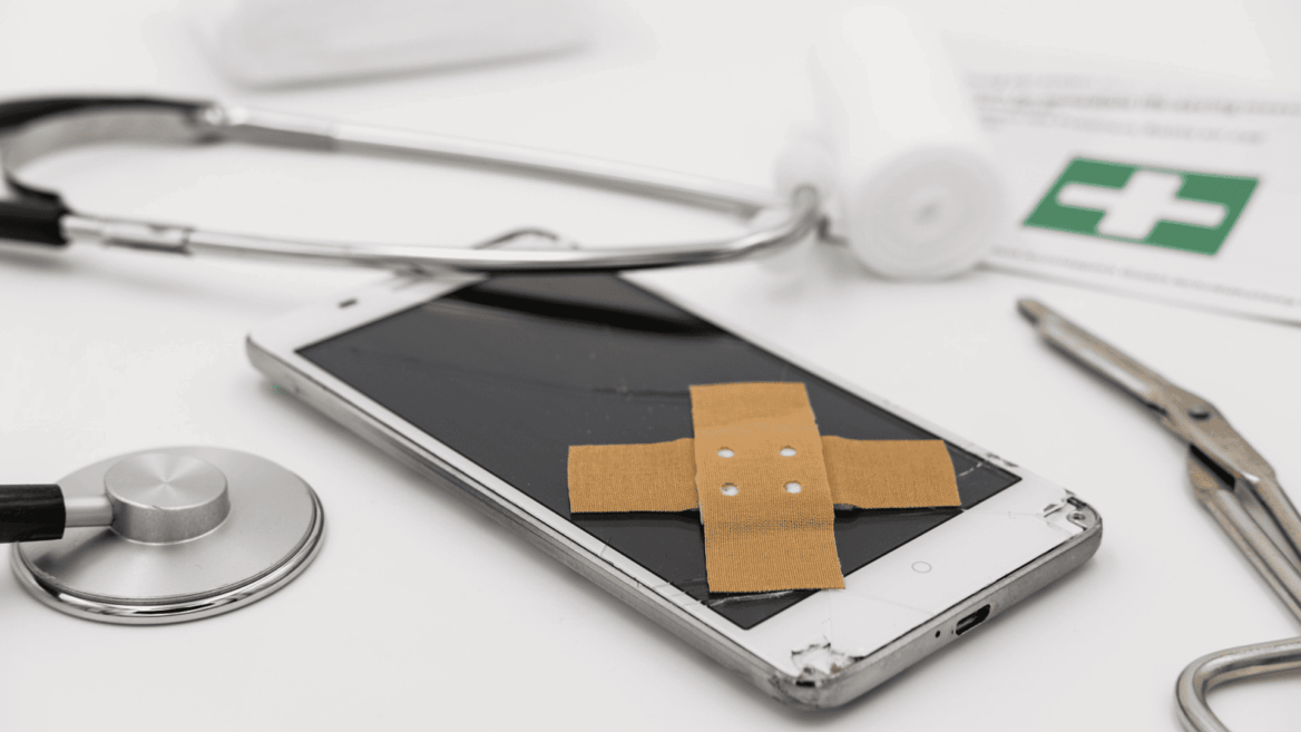 teléfono roto vendado entre instrumentos médicos