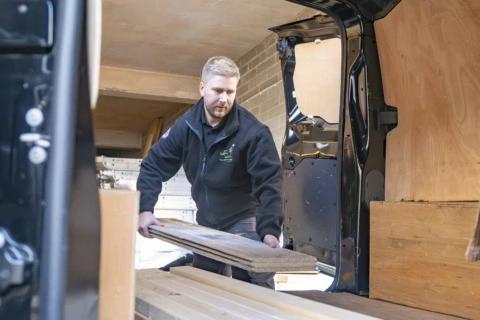 carpenter loading wooden planks into van