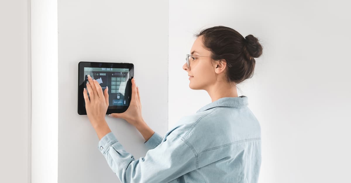 woman using wall mounted smart home security panel