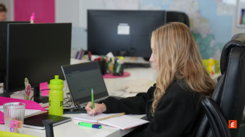 blonde woman taking notes at office desk