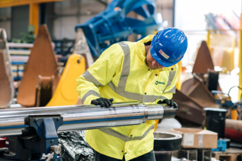 technician inspecting polished chrome shaft in workshop