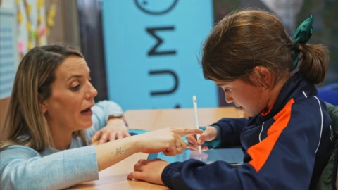 enseignante guidant une Élève sur tablette tactile