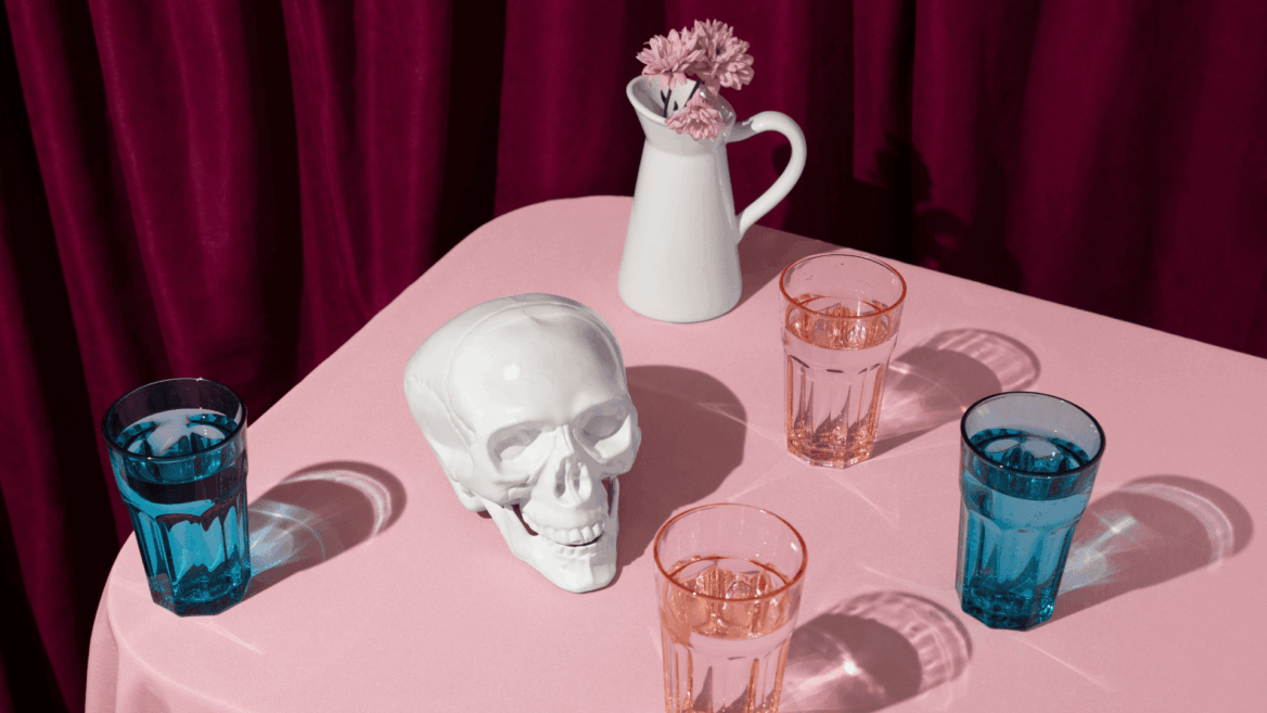 calavera cerámica y vasos facetados sobre tela rosa