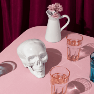 calavera cerámica y vasos facetados sobre tela rosa