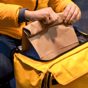 manos colocando bolsa de papel en bolsa térmica amarilla