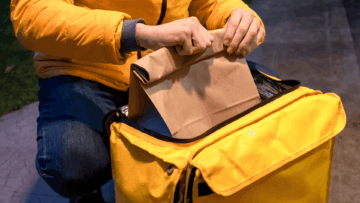 manos colocando bolsa de papel en bolsa térmica amarilla