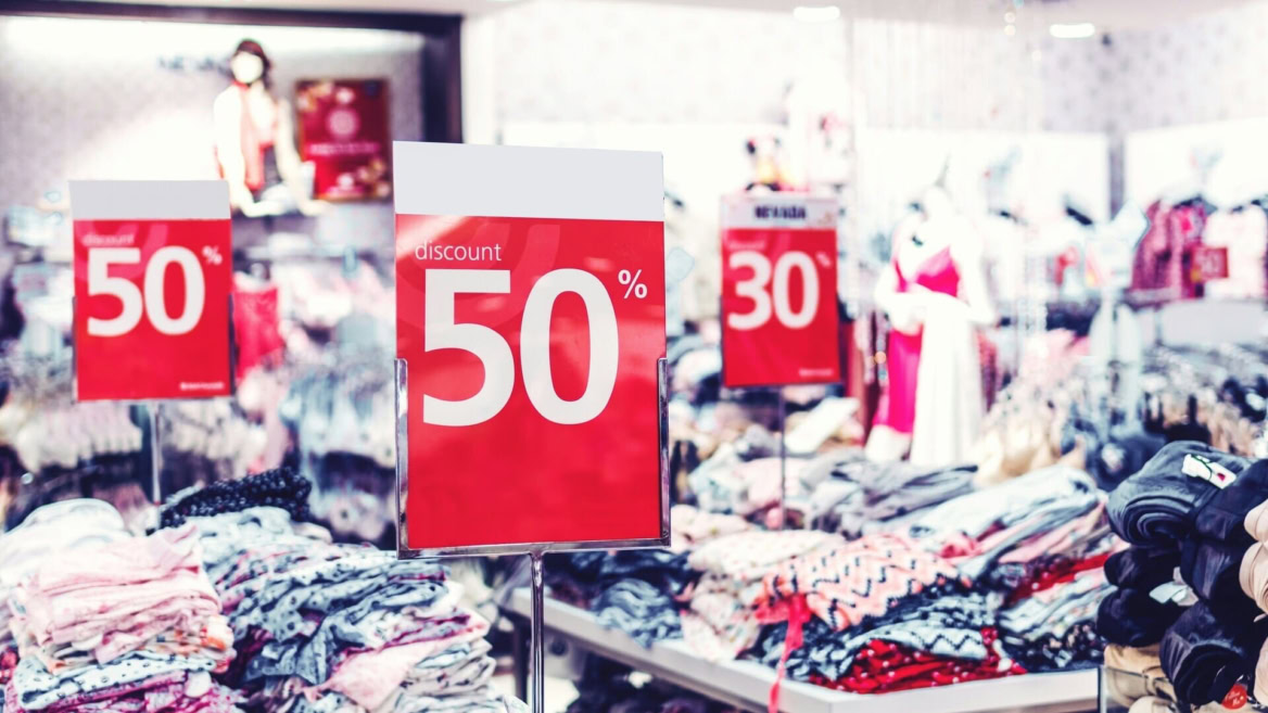 soldes 50% : piles de vêtements en boutique