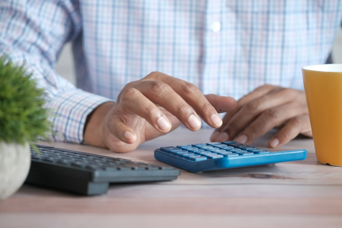 calculs au bureau : mains et calculatrice bleue