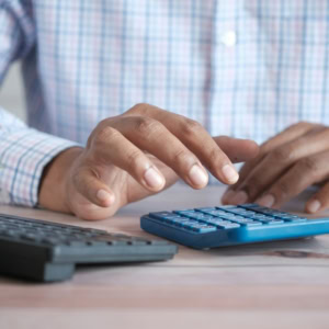 calculs au bureau : mains et calculatrice bleue