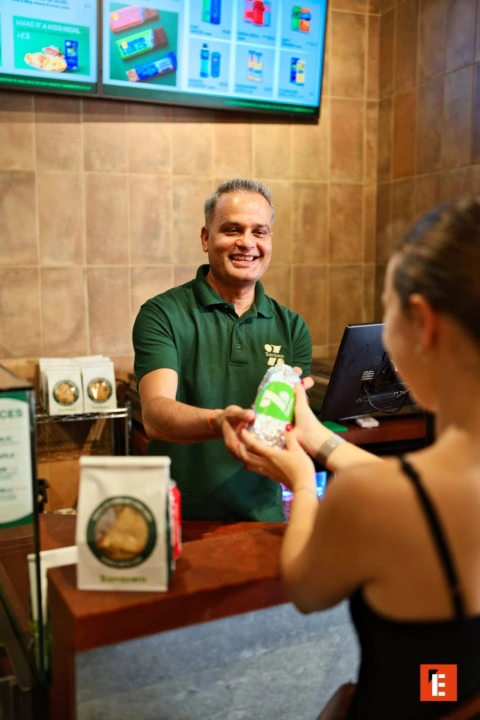 friendly counter staff handing wrapped burrito to customer