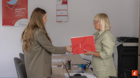 uścisk dłoni przy przekazaniu czerwonej teczki