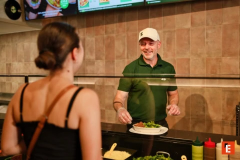 smiling server serving fresh bowl at counter