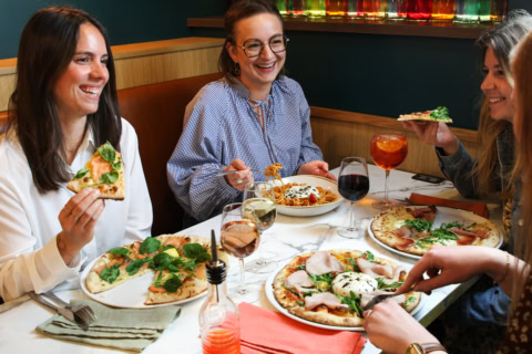 femmes en dîner convivial avec pizzas et vins