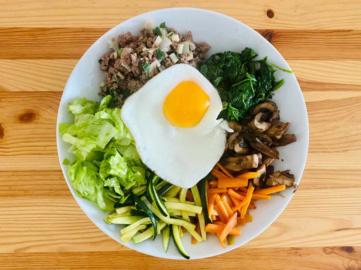 bunte frühstücksbowl mit spiegelei, gemüse und hackfleisch