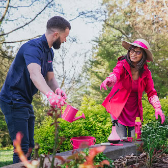 couple watering raised garden bed in pink gloves