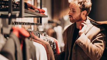 hombre elegante elige abrigo en boutique cálida