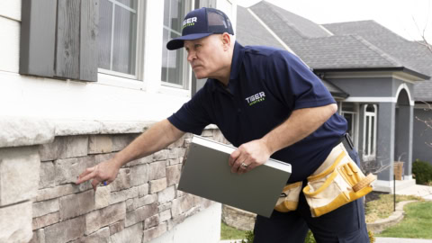 professional inspecting stone veneer on home exterior