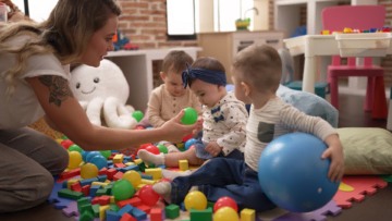 caregiver and toddlers playing in colorful daycare playroom
