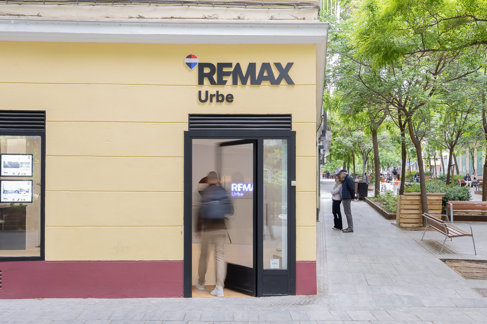 oficina remax con puerta abierta en calle arbolada