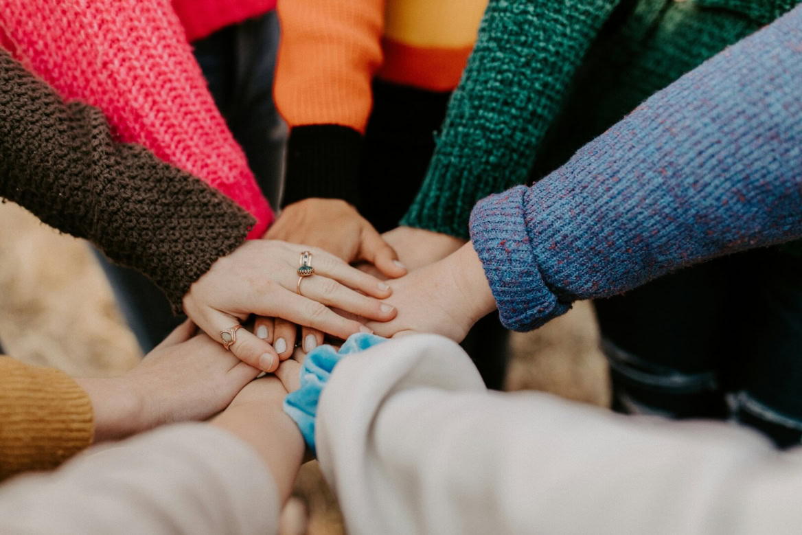 mains entrelacées : solidarité en pulls colorés