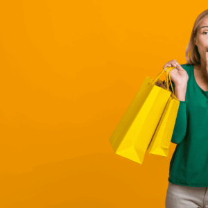 mujer sorprendida con bolsas amarillas sobre fondo naranja