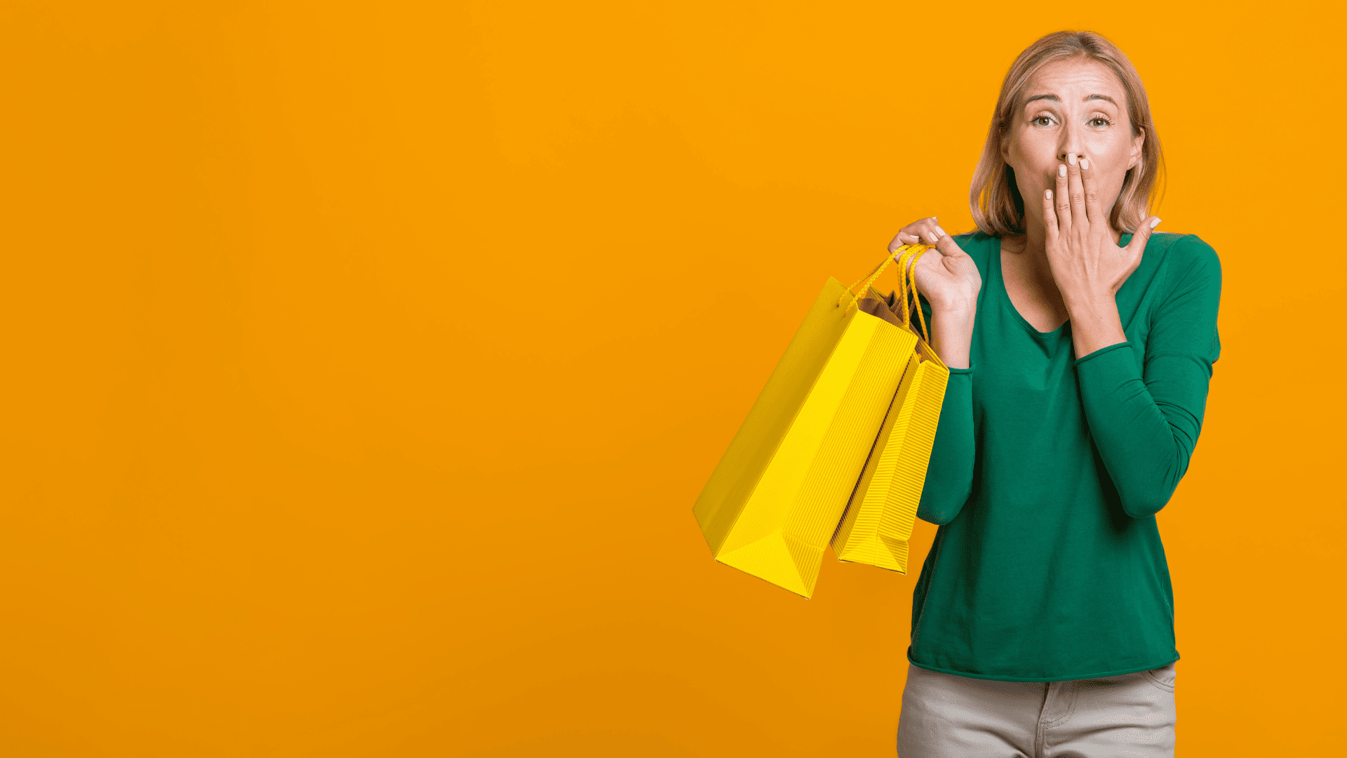 mujer sorprendida con bolsas amarillas sobre fondo naranja
