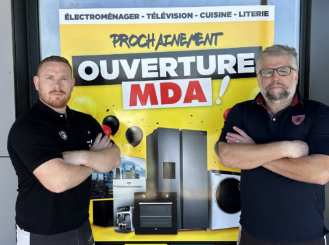 deux employés devant laffiche douverture mda