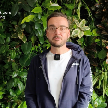 mann mit mikrofon vor grüner pflanzenwand