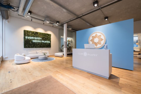 moderne pilates rezeption mit lounge und pflanzenwand